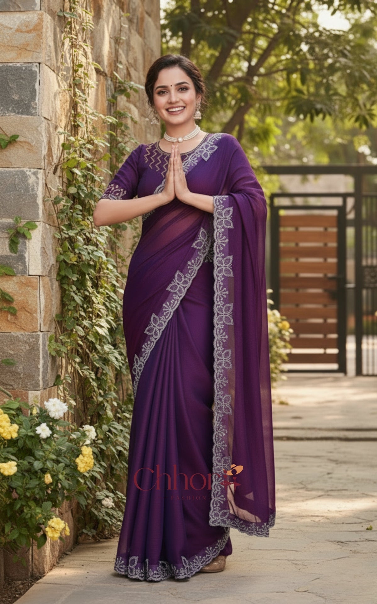 Woman wearing a purple saree with a stone wall and greenery in the background | Chhorii Fashion